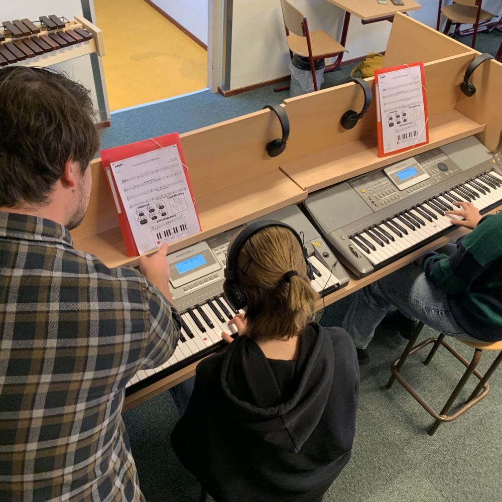 Muziekdocent Jop Ostendorf legt noten uit aan zijn leerling aan het keyboard